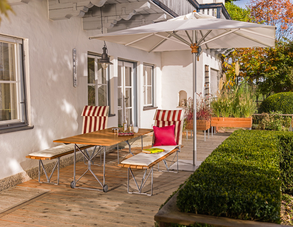Kleine, Überdachte Landhaus Terrasse hinter dem Haus mit Kübelpflanzen in München