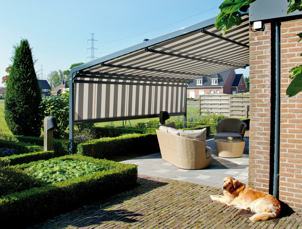 Réalisation d'une terrasse latérale design de taille moyenne avec un auvent.