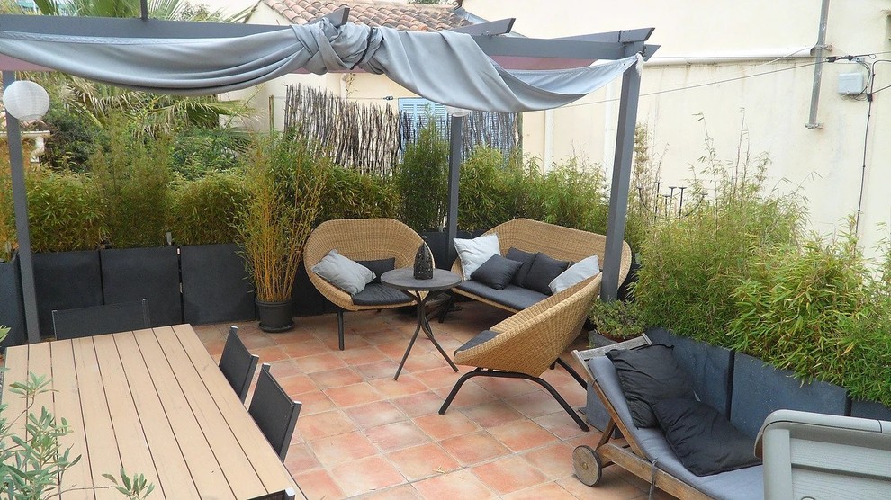 Imagen de patio minimalista de tamaño medio en patio con jardín de macetas, suelo de baldosas y pérgola