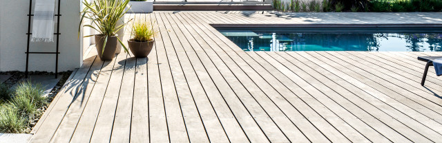 Une terrasse en bois avec pergola au bord de la piscine