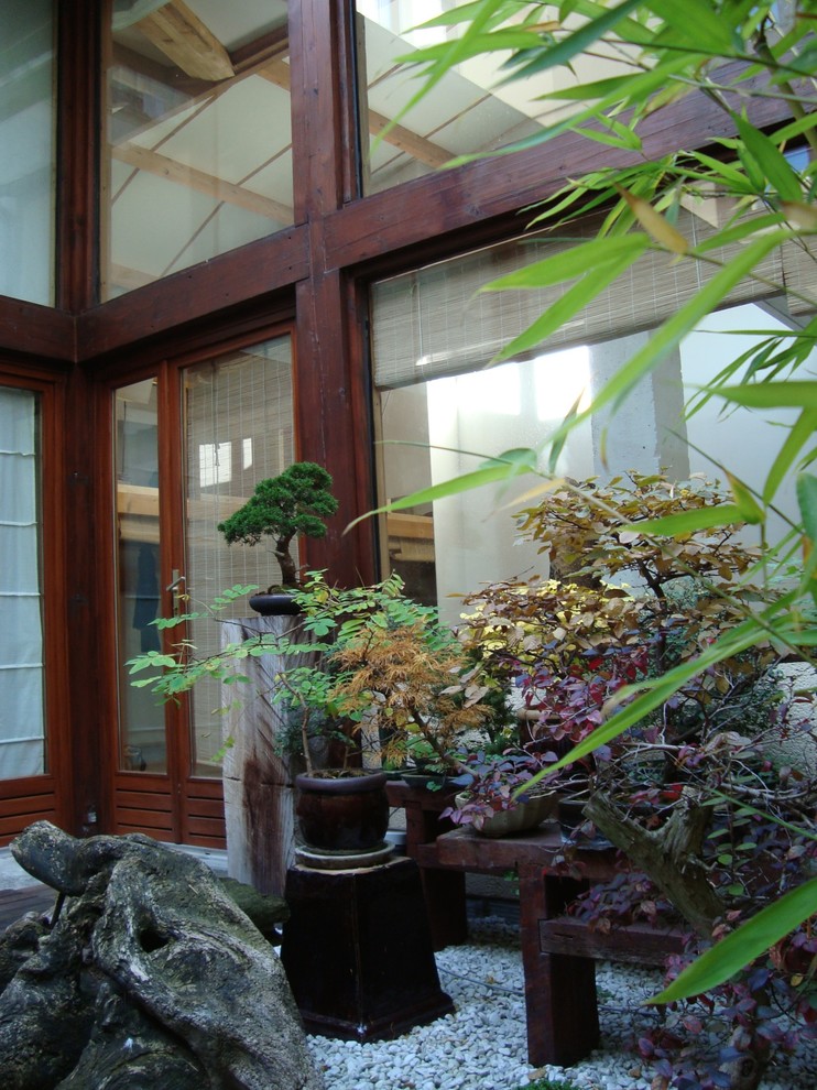 Immagine di un grande patio o portico etnico in cortile con un giardino in vaso, ghiaia e un tetto a sbalzo