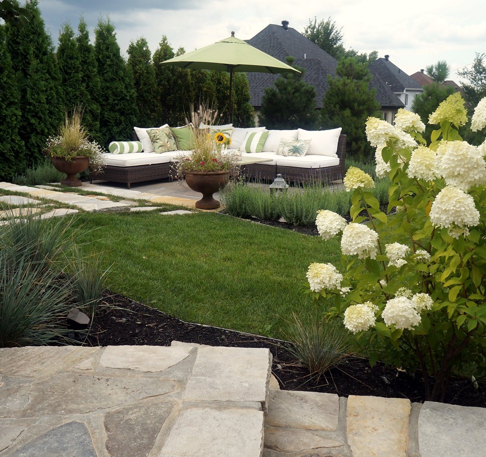 Large transitional courtyard stone patio photo in Montreal with no cover