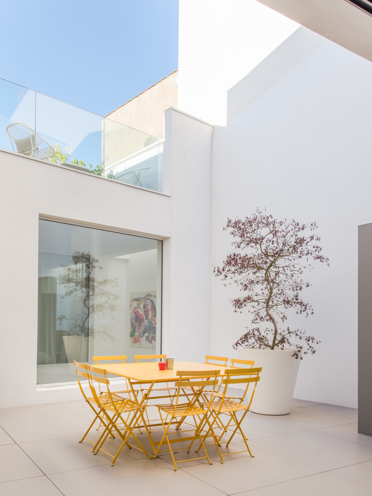 Inspiration pour une terrasse minimaliste de taille moyenne avec une cour, du carrelage et aucune couverture.