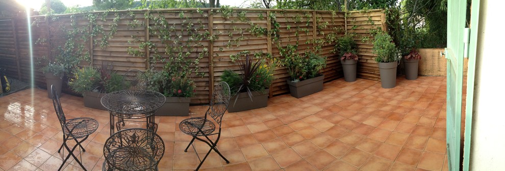 This is an example of a medium sized mediterranean back patio in Nice with a fire feature, tiled flooring and an awning.