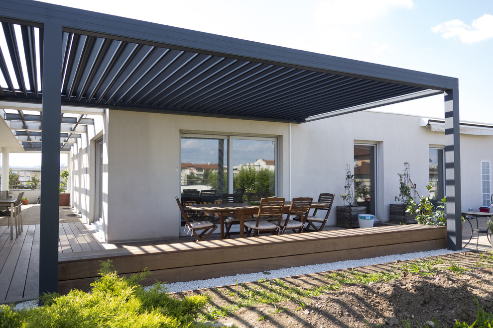 This is an example of a medium sized modern back patio in Lyon with decking and a pergola.