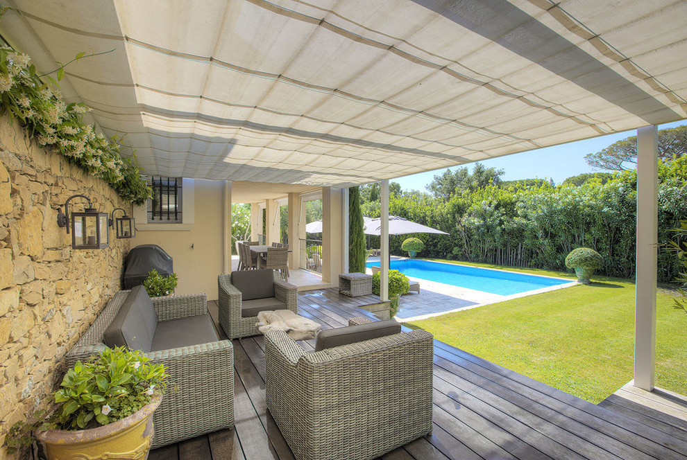 Esempio di un patio o portico mediterraneo con pedane e un parasole