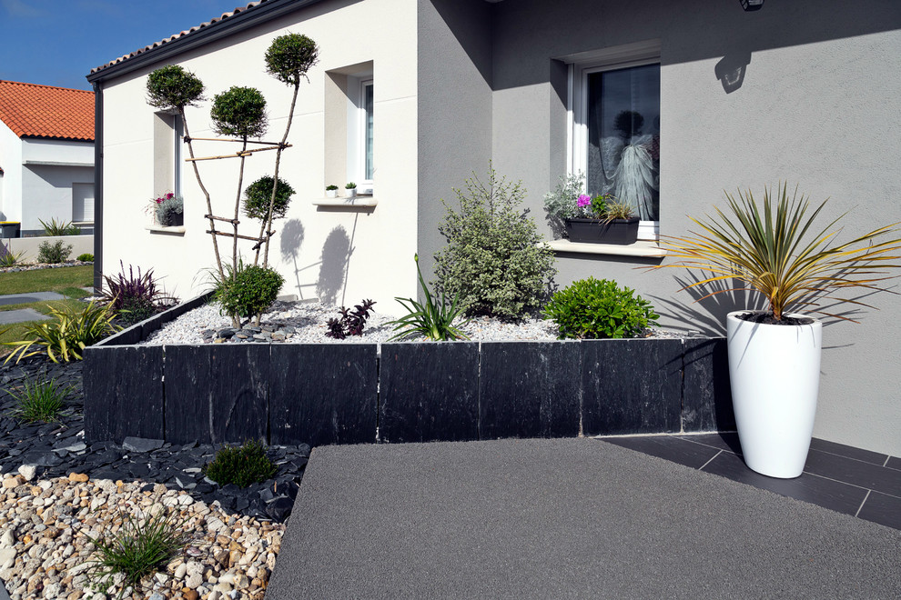 Idée de décoration pour une terrasse avec des plantes en pots avant minimaliste de taille moyenne avec une dalle de béton et aucune couverture.