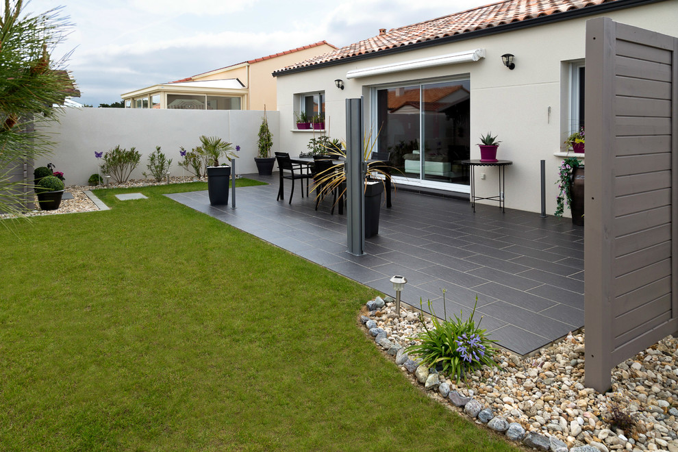 Imagen de patio minimalista de tamaño medio en patio trasero y anexo de casas con jardín de macetas y losas de hormigón