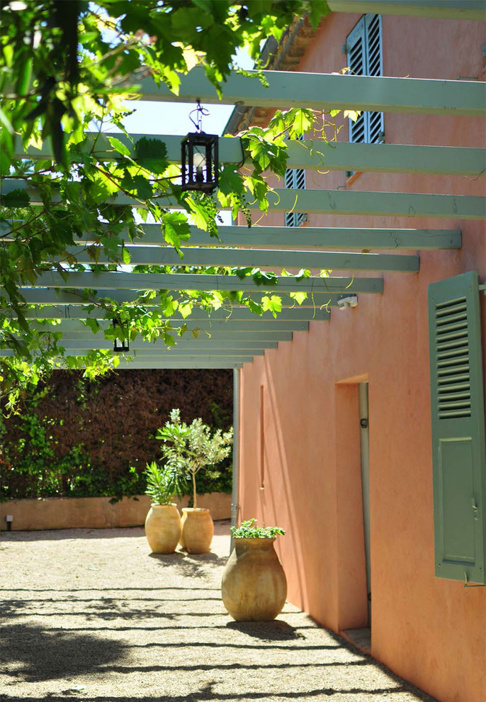 Immagine di un patio o portico mediterraneo di medie dimensioni e davanti casa con un giardino in vaso, ghiaia e una pergola