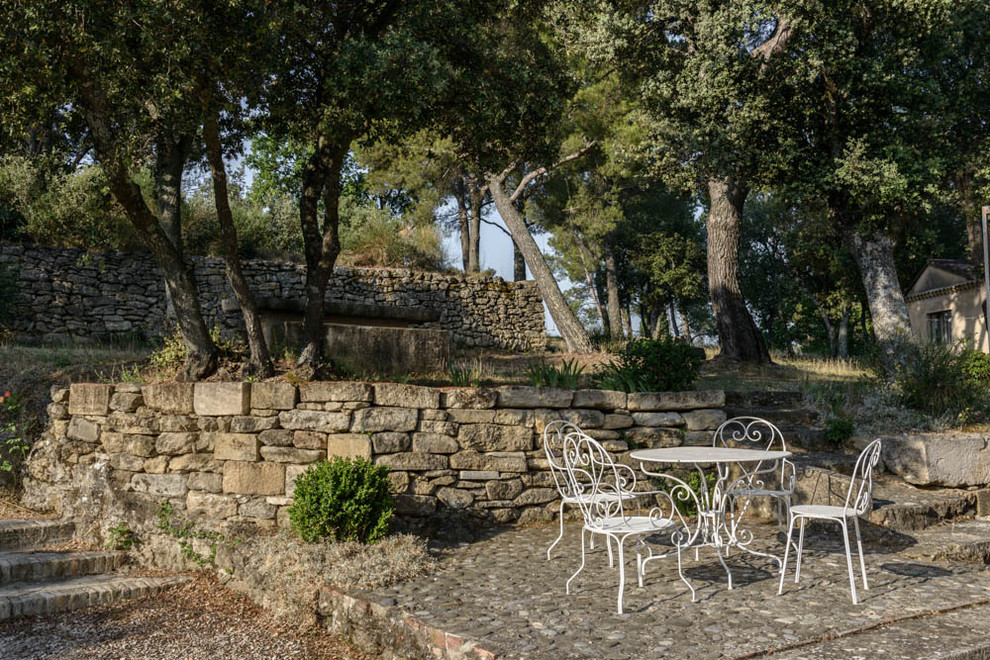 Foto de patio mediterráneo sin cubierta en patio trasero con adoquines de piedra natural