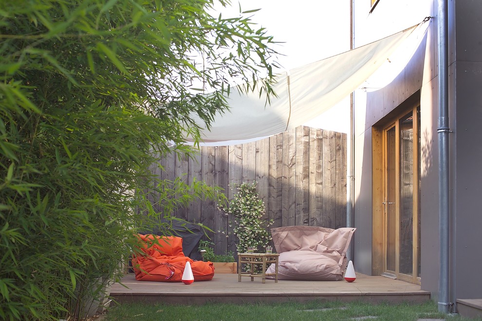 Foto de patio contemporáneo de tamaño medio en patio lateral con entablado y toldo