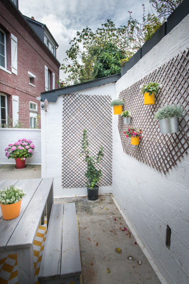 Patio container garden - mid-sized transitional courtyard patio container garden idea in Le Havre with an awning