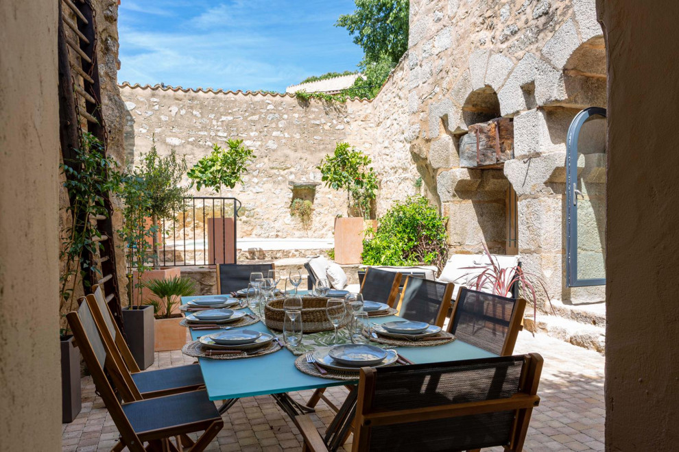 Modelo de patio mediterráneo pequeño sin cubierta en patio trasero con jardín de macetas y adoquines de piedra natural