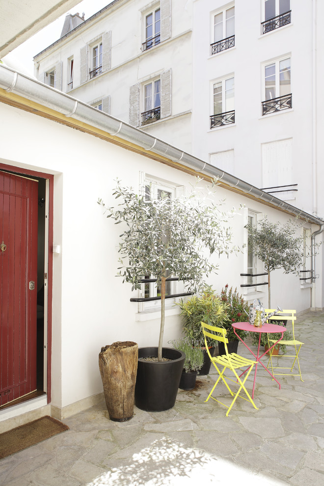 Immagine di un patio o portico mediterraneo davanti casa con un giardino in vaso e pavimentazioni in pietra naturale