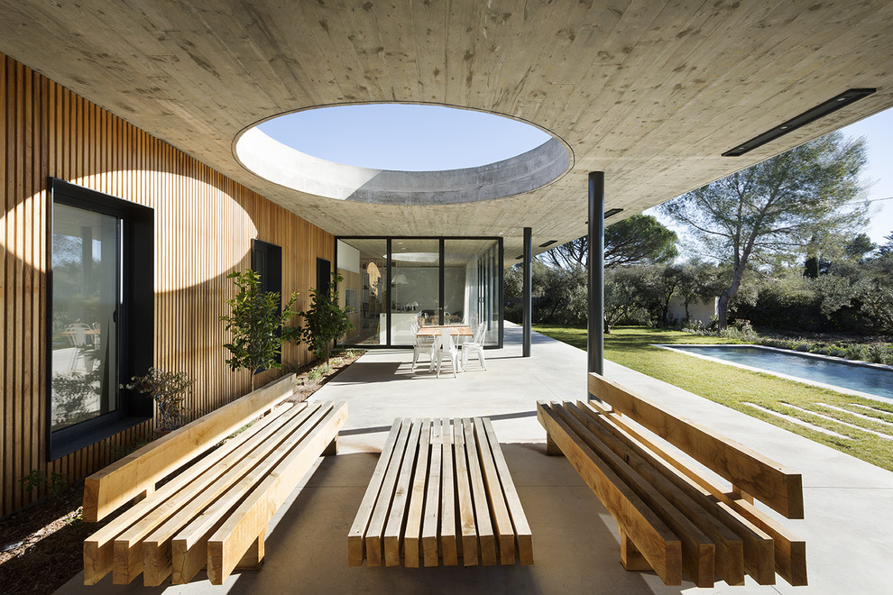Идея дизайна: двор на заднем дворе в стиле модернизм с покрытием из бетонных плит и навесом