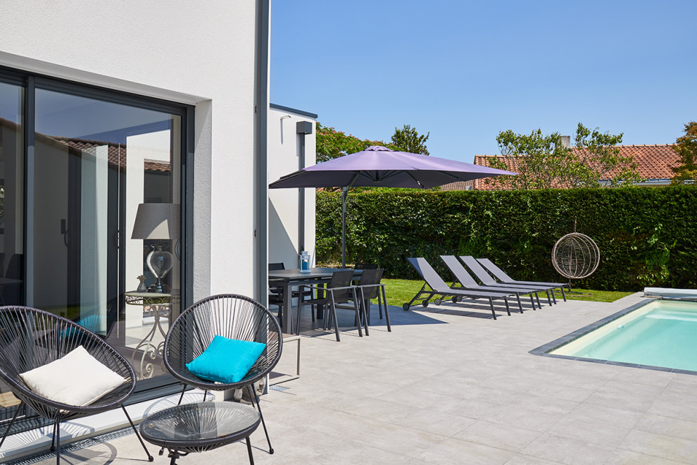 This is an example of a large scandinavian back patio in Nantes with tiled flooring.