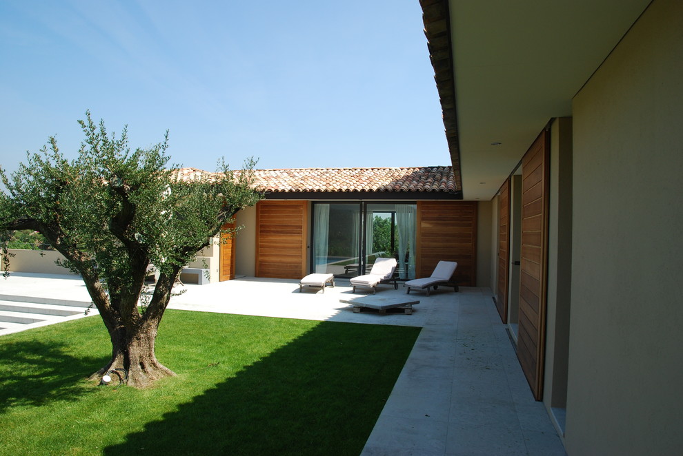 Exemple d'une grande terrasse arrière méditerranéenne avec une dalle de béton.