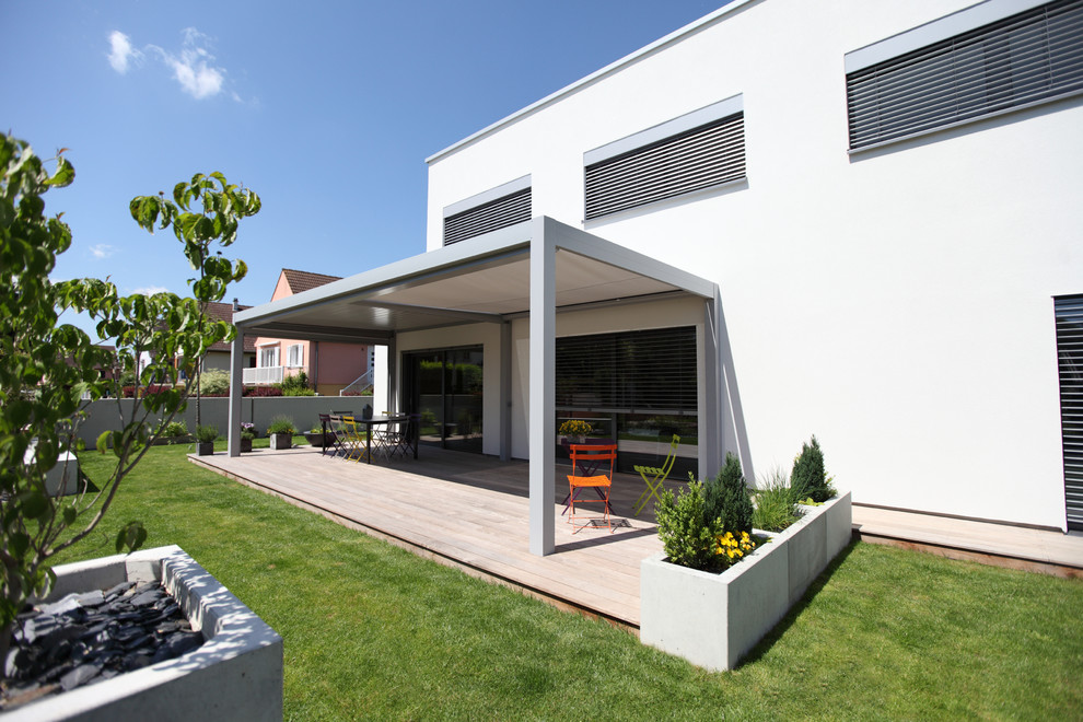 Contemporary side patio in Strasbourg with a potted garden, decking and a pergola.