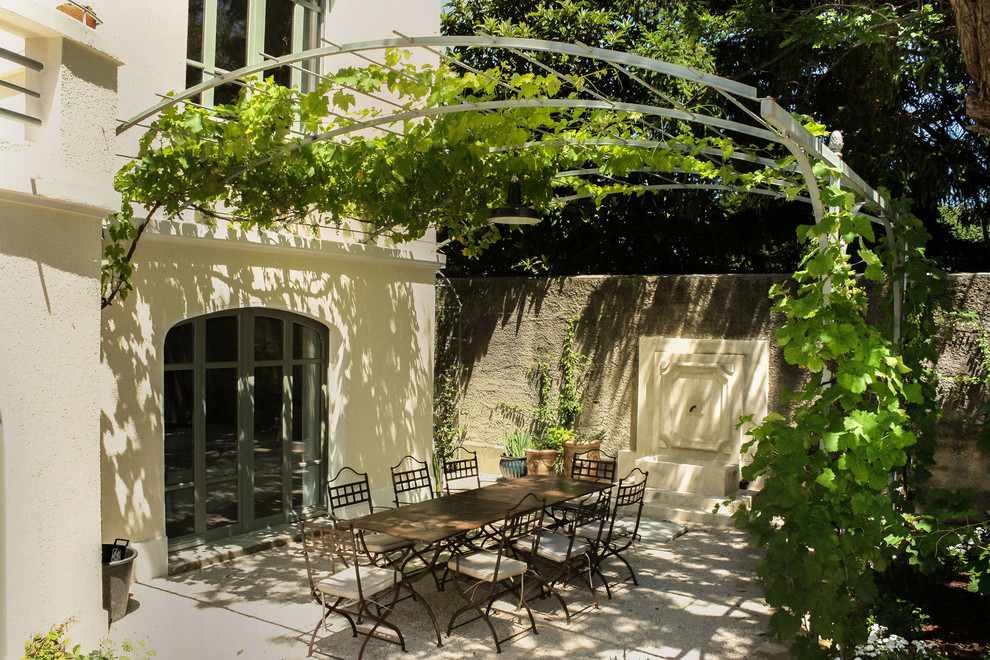 Design ideas for a large mediterranean front patio in Paris with a water feature and a pergola.