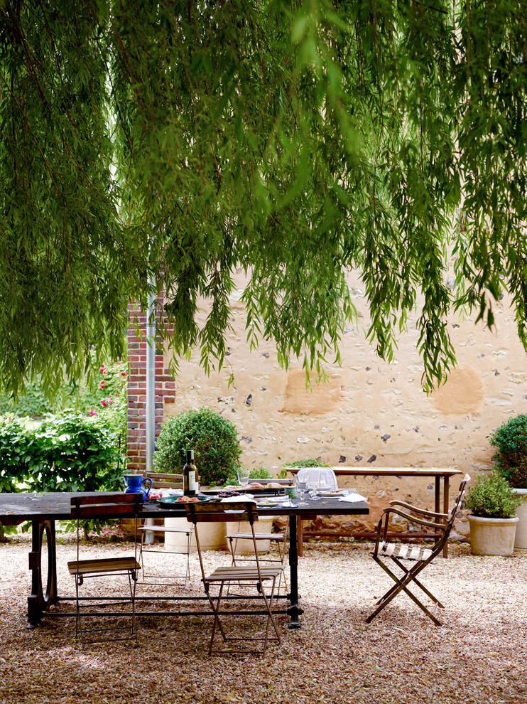 This is an example of a country back patio in Paris with gravel, no cover and a potted garden.