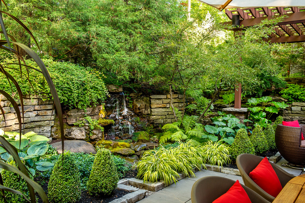 Ejemplo de patio exótico de tamaño medio en patio con fuente, adoquines de piedra natural y pérgola