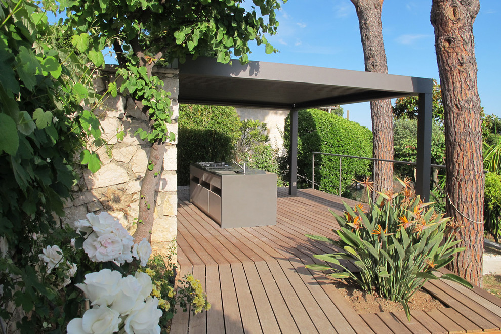 Modelo de terraza mediterránea grande en patio trasero con cocina exterior y pérgola