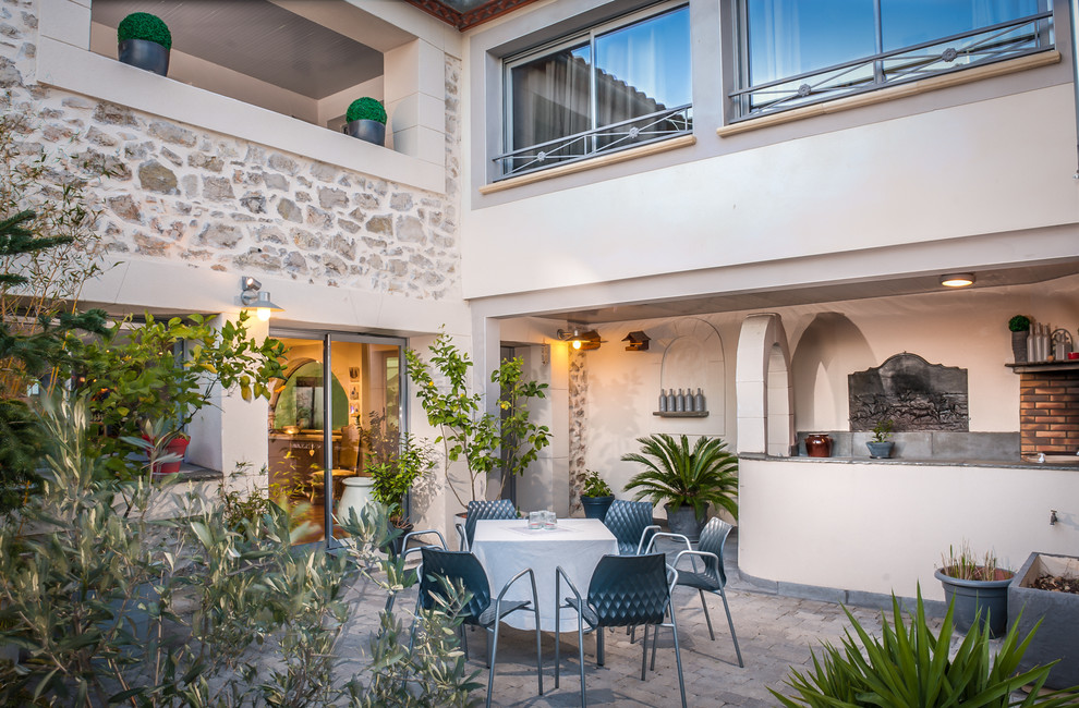 Cette photo montre une terrasse méditerranéenne de taille moyenne avec une cuisine d'été, une cour, des pavés en pierre naturelle et aucune couverture.