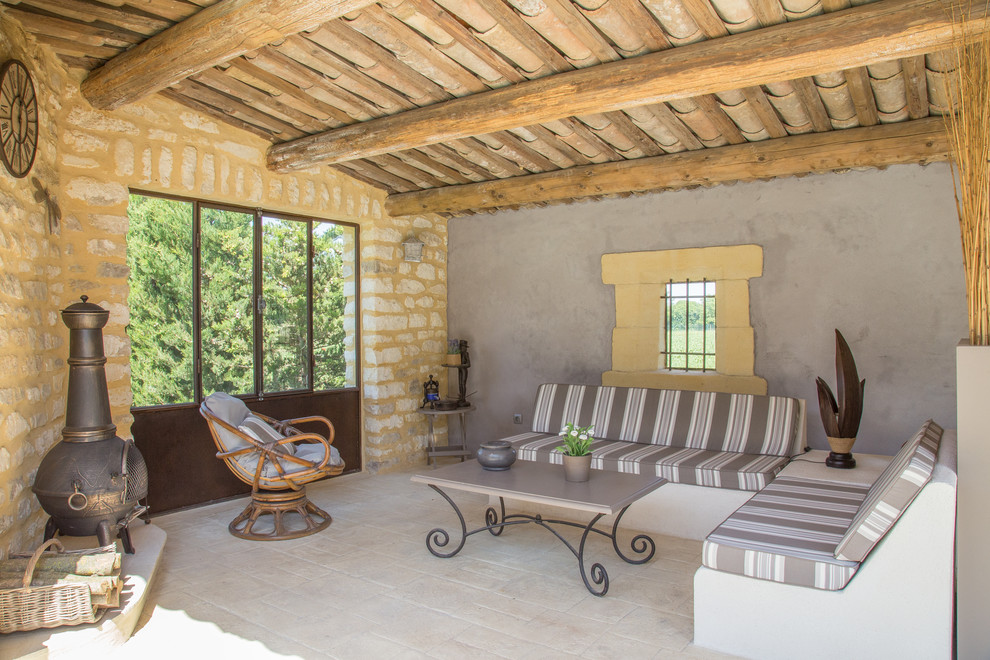 Inspiration pour une terrasse méditerranéenne de taille moyenne avec une extension de toiture, des pavés en pierre naturelle et une cheminée.
