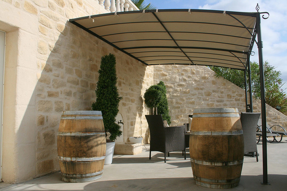 Ispirazione per un patio o portico mediterraneo con un giardino in vaso, lastre di cemento e un parasole