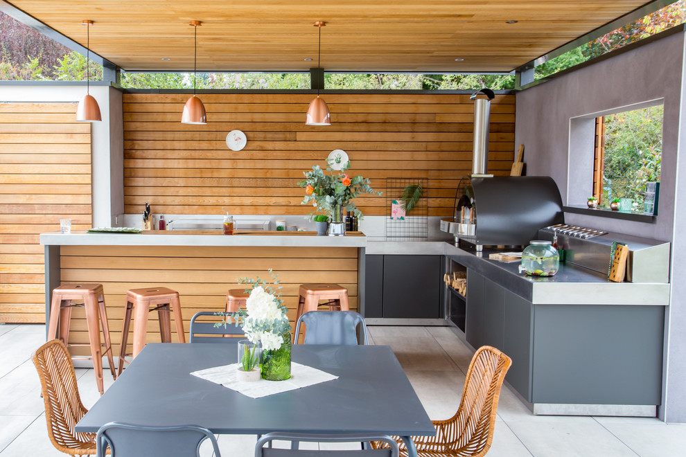 Inspiration pour une grande terrasse arrière design avec une cuisine d'été, du carrelage et une pergola.