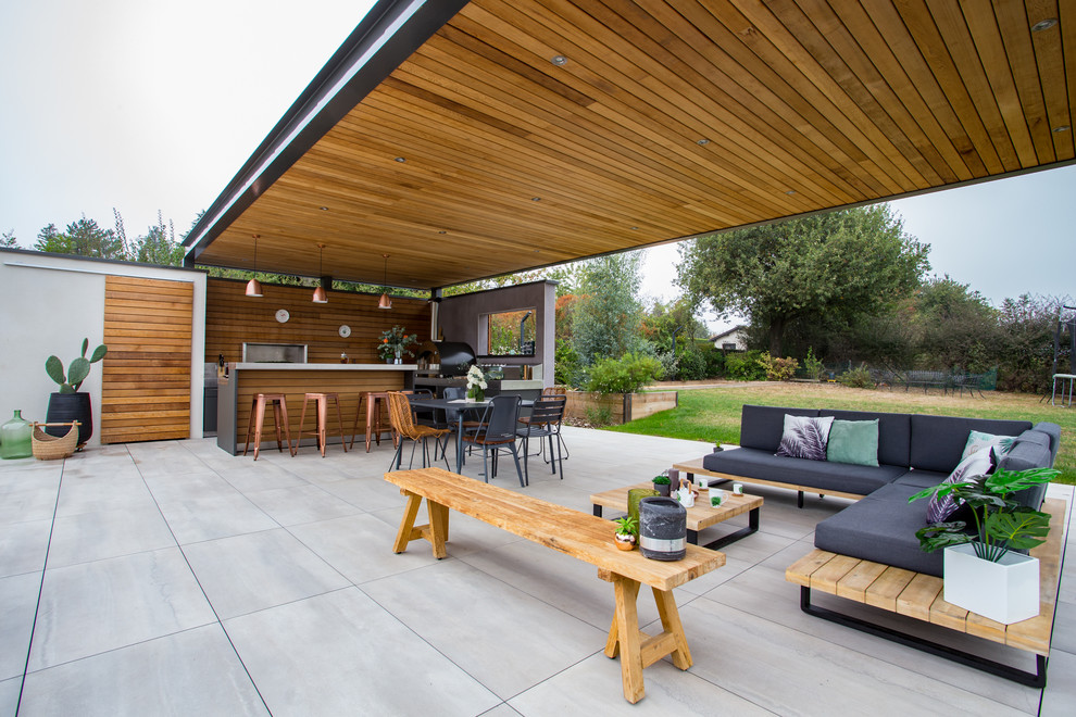Modelo de patio contemporáneo de tamaño medio en patio trasero con cocina exterior, suelo de baldosas y pérgola