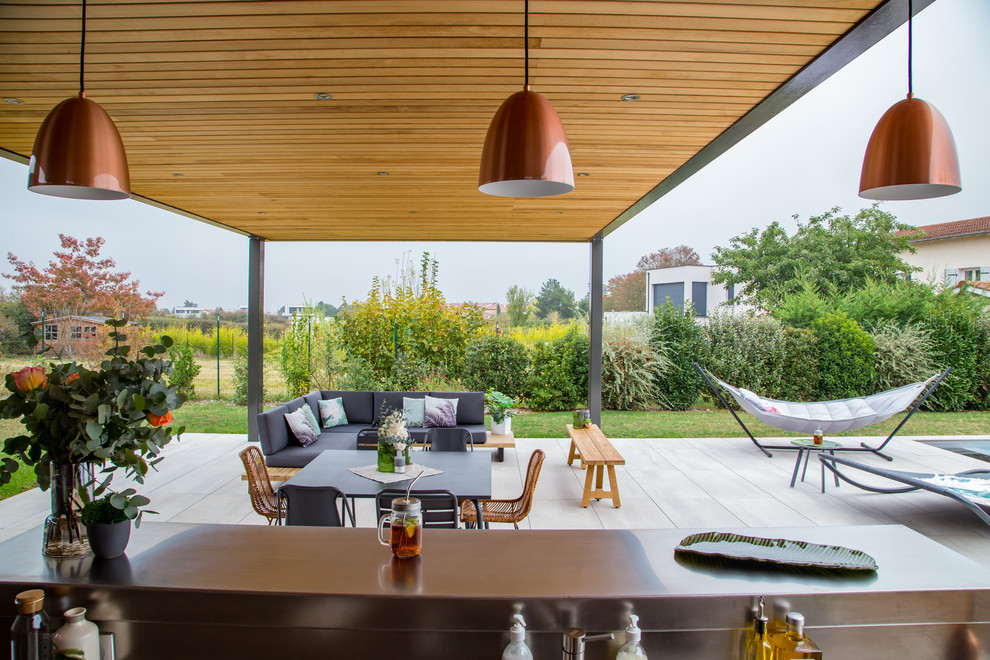 Cette photo montre une terrasse arrière tendance de taille moyenne avec une cuisine d'été, du carrelage et une pergola.
