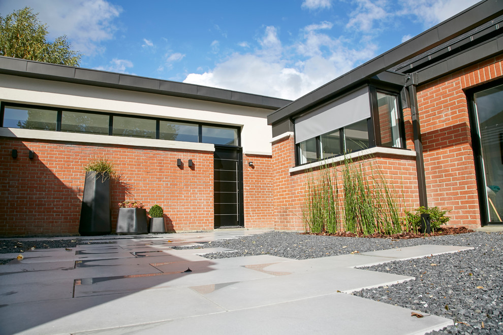 Cette photo montre une terrasse tendance de taille moyenne avec une cour, du gravier et une extension de toiture.