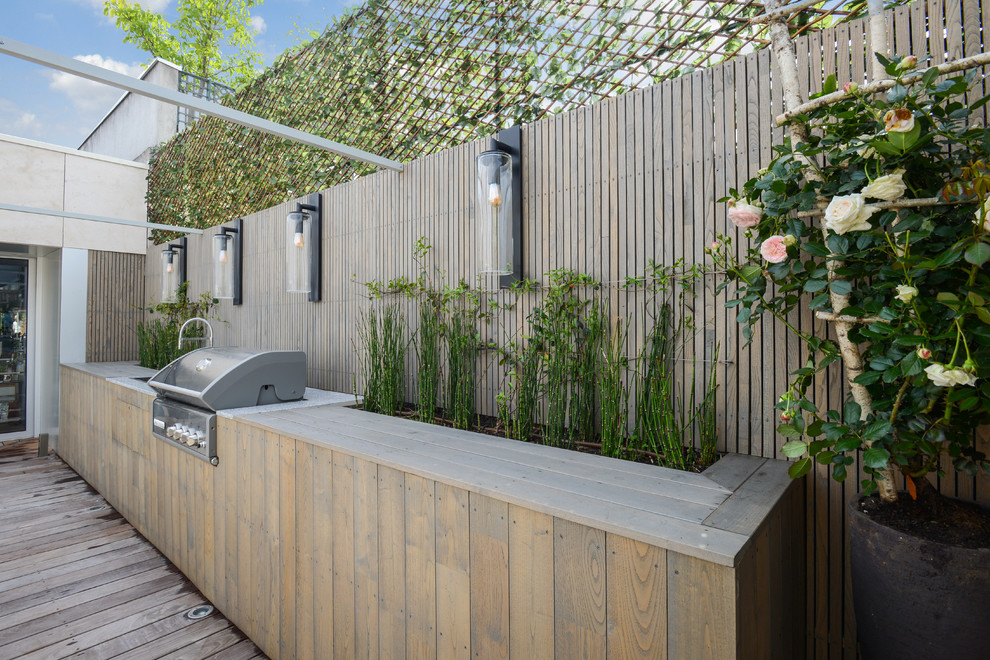 This is an example of a large modern patio in Paris with an outdoor kitchen, decking and no cover.