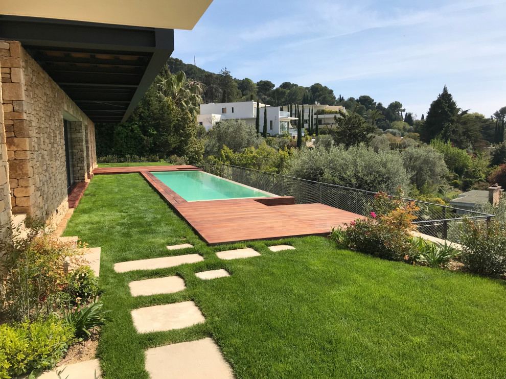 Foto de terraza planta baja tropical de tamaño medio sin cubierta en patio con jardín vertical y barandilla de metal