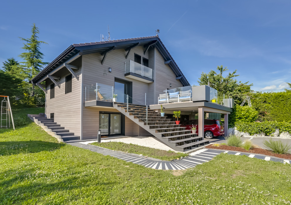 Inspiration pour une grande façade de maison beige minimaliste en bois à deux étages et plus avec un toit à deux pans, un toit en tuile et un toit gris.