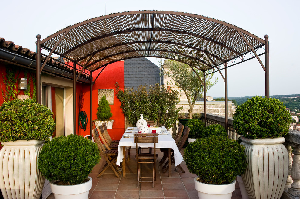 Inspiration för mellanstora klassiska terrasser, med en pergola och utekrukor