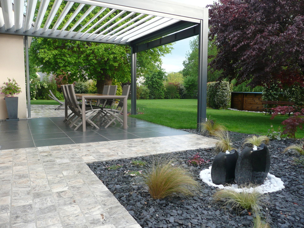 Example of a mid-sized minimalist backyard tile patio design in Angers with a pergola