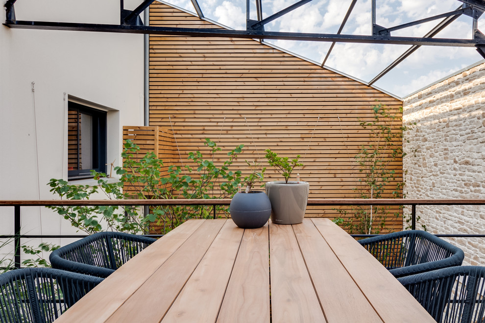 This is an example of a large contemporary courtyard patio in Nantes with an outdoor kitchen, decking and a roof extension.