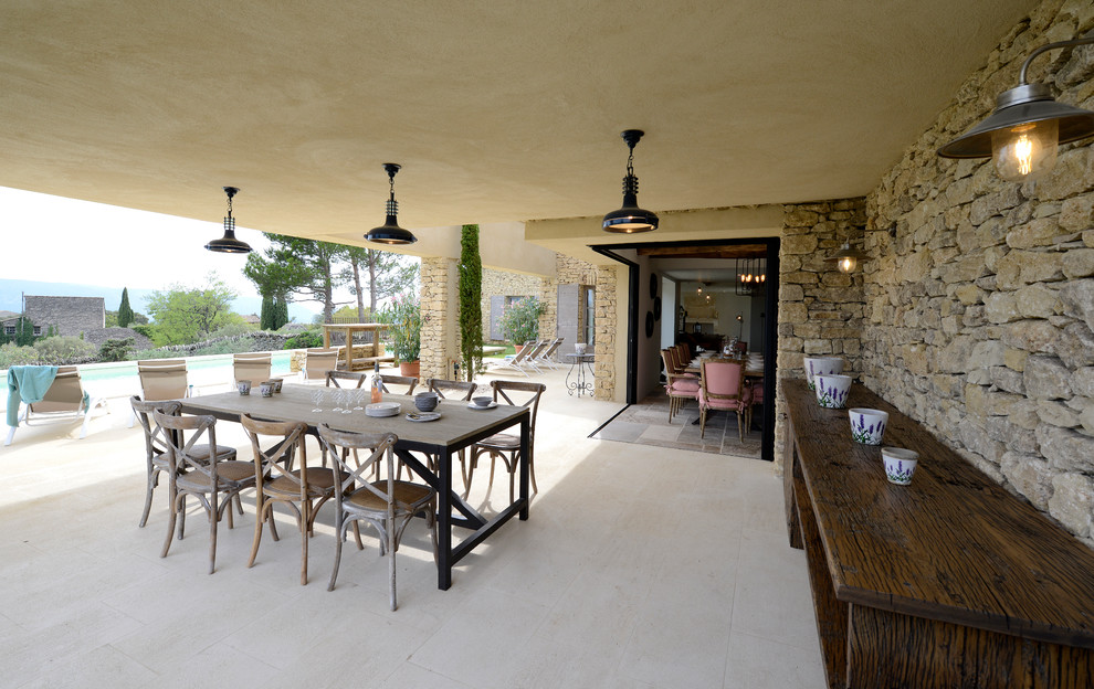 Idée de décoration pour une grande terrasse arrière méditerranéenne avec une cuisine d'été, des pavés en pierre naturelle et une extension de toiture.