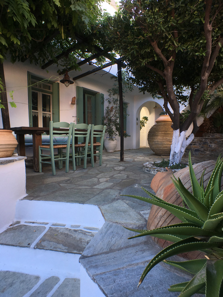 Inspiration pour une terrasse avec des plantes en pots avant méditerranéenne de taille moyenne avec des pavés en pierre naturelle et une pergola.