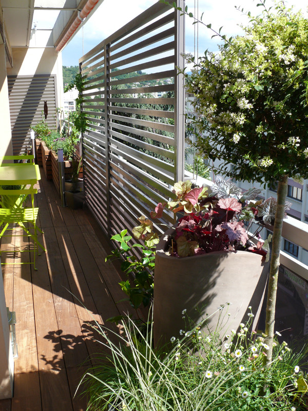 На фото: маленький двор на боковом дворе в современном стиле с растениями в контейнерах и настилом для на участке и в саду с