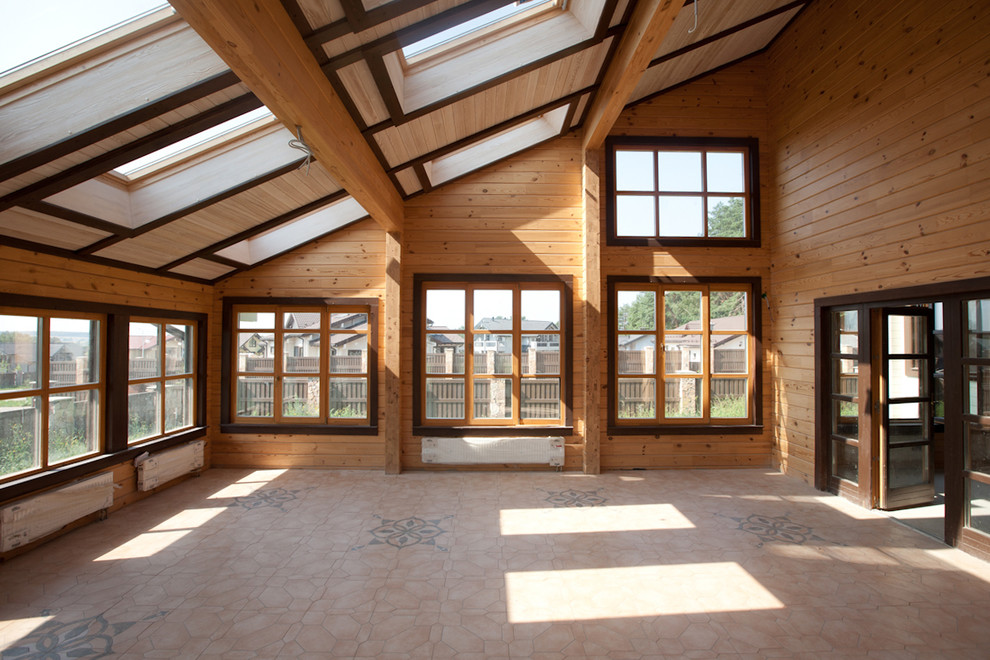 На фото: большая терраса с полом из керамической плитки, угловым камином, потолочным окном и бежевым полом