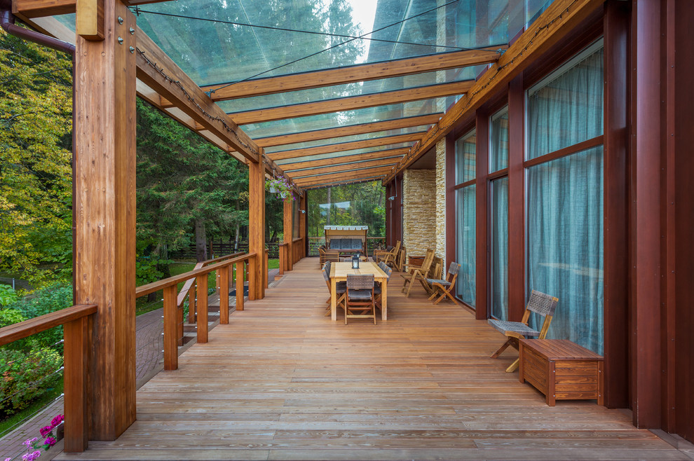 Ejemplo de terraza planta baja ecléctica grande en anexo de casas y patio con barandilla de madera