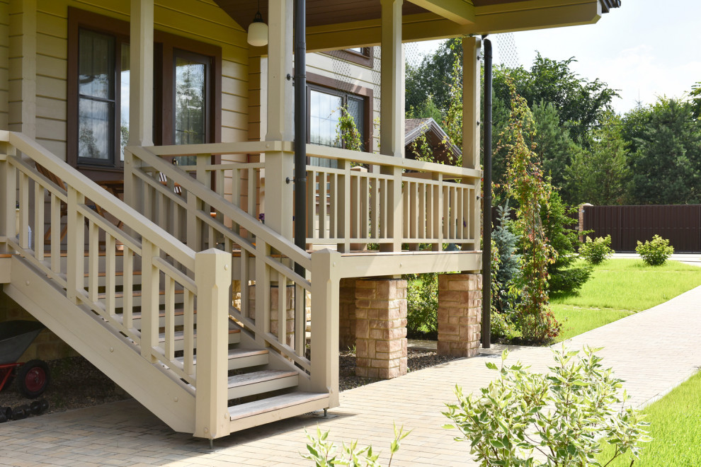 Diseño de terraza planta baja de estilo de casa de campo de tamaño medio en patio y anexo de casas con barandilla de madera