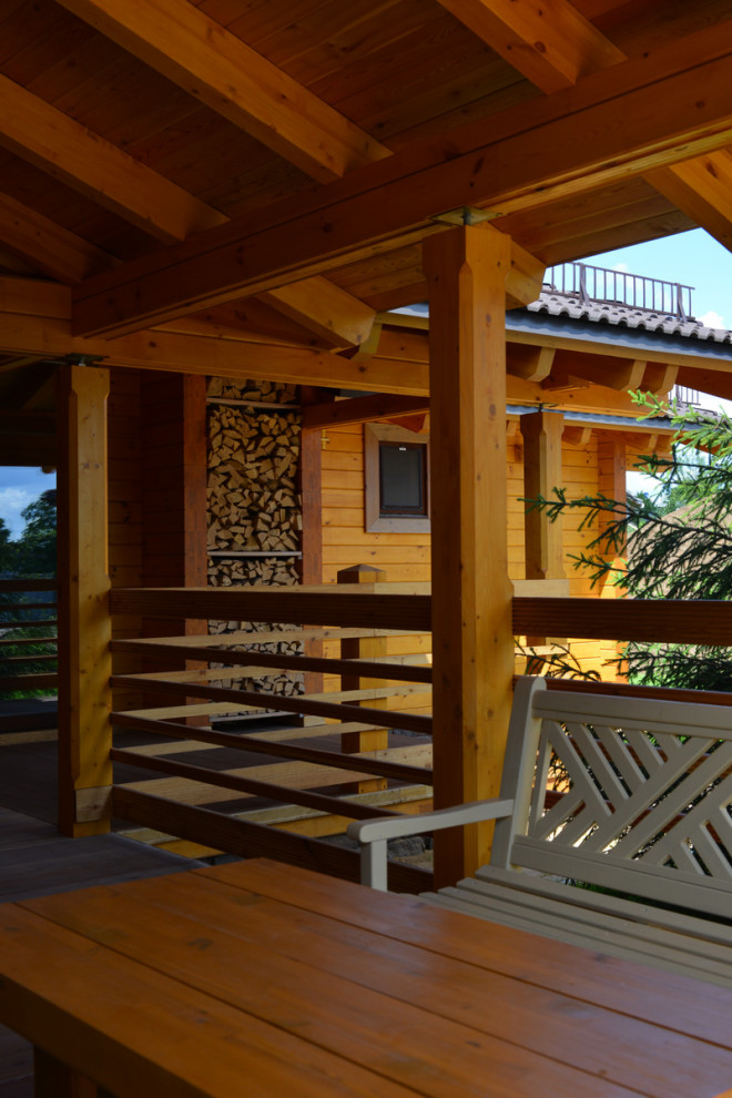 Exempel på en mellanstor lantlig terrass, med takförlängning och räcke i trä