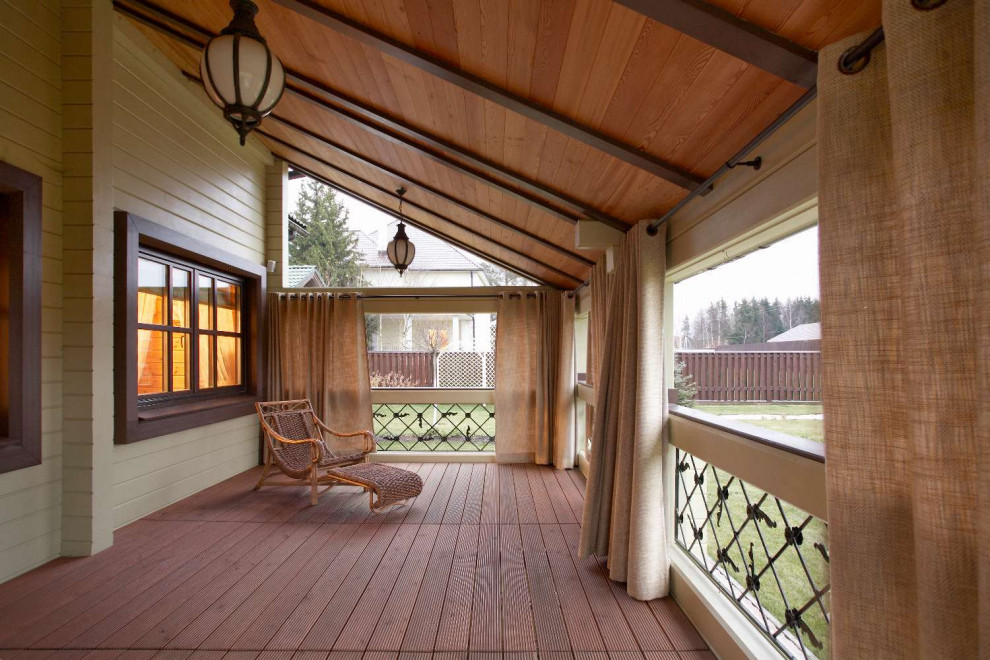Imagen de terraza planta baja de estilo de casa de campo de tamaño medio en patio y anexo de casas con barandilla de madera