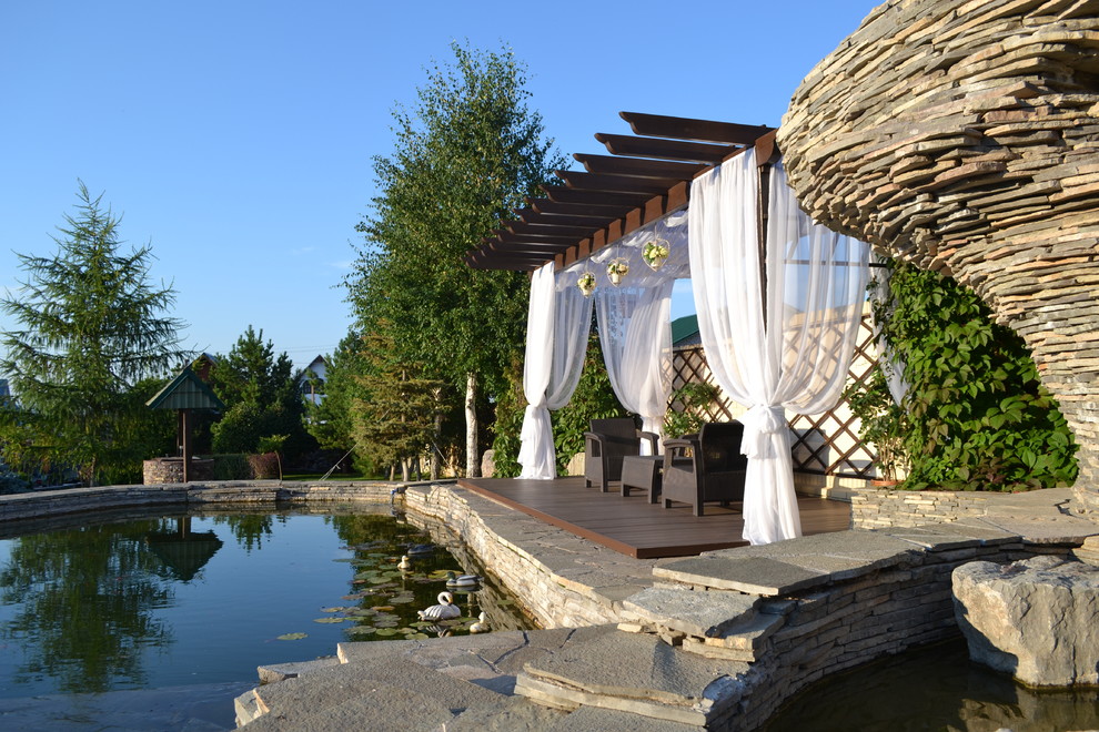 他の地域にある地中海スタイルのおしゃれな裏庭のデッキ (パーゴラ) の写真