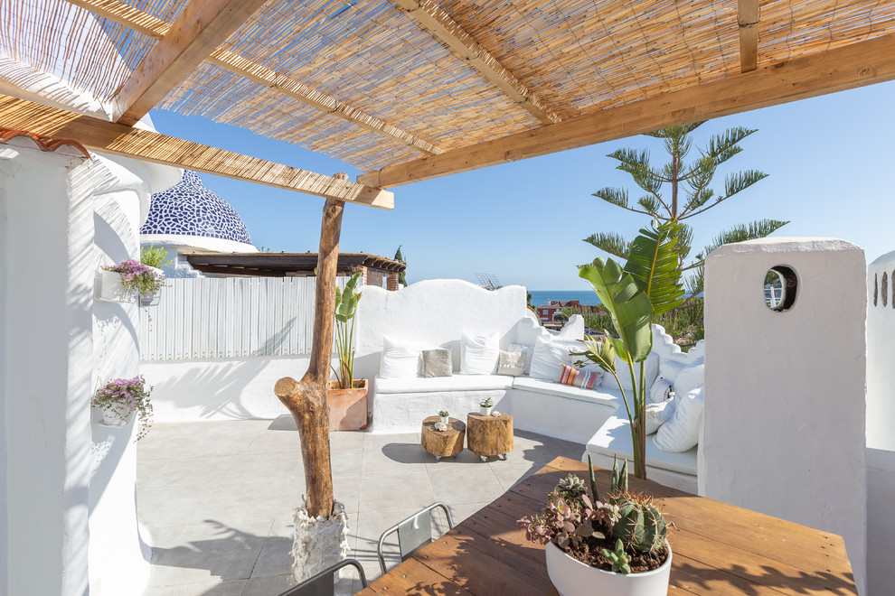 Ejemplo de terraza mediterránea de tamaño medio en azotea con jardín de macetas y pérgola