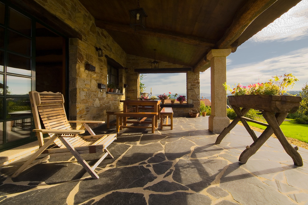 Ejemplo de terraza rural de tamaño medio en patio trasero y anexo de casas con jardín de macetas y adoquines de piedra natural